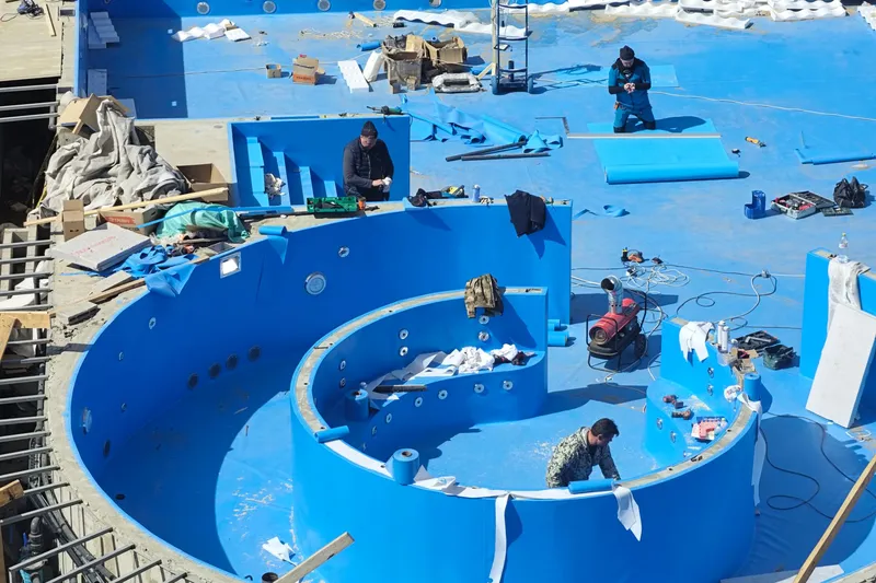 Workers building a swimming pool with a blue interior